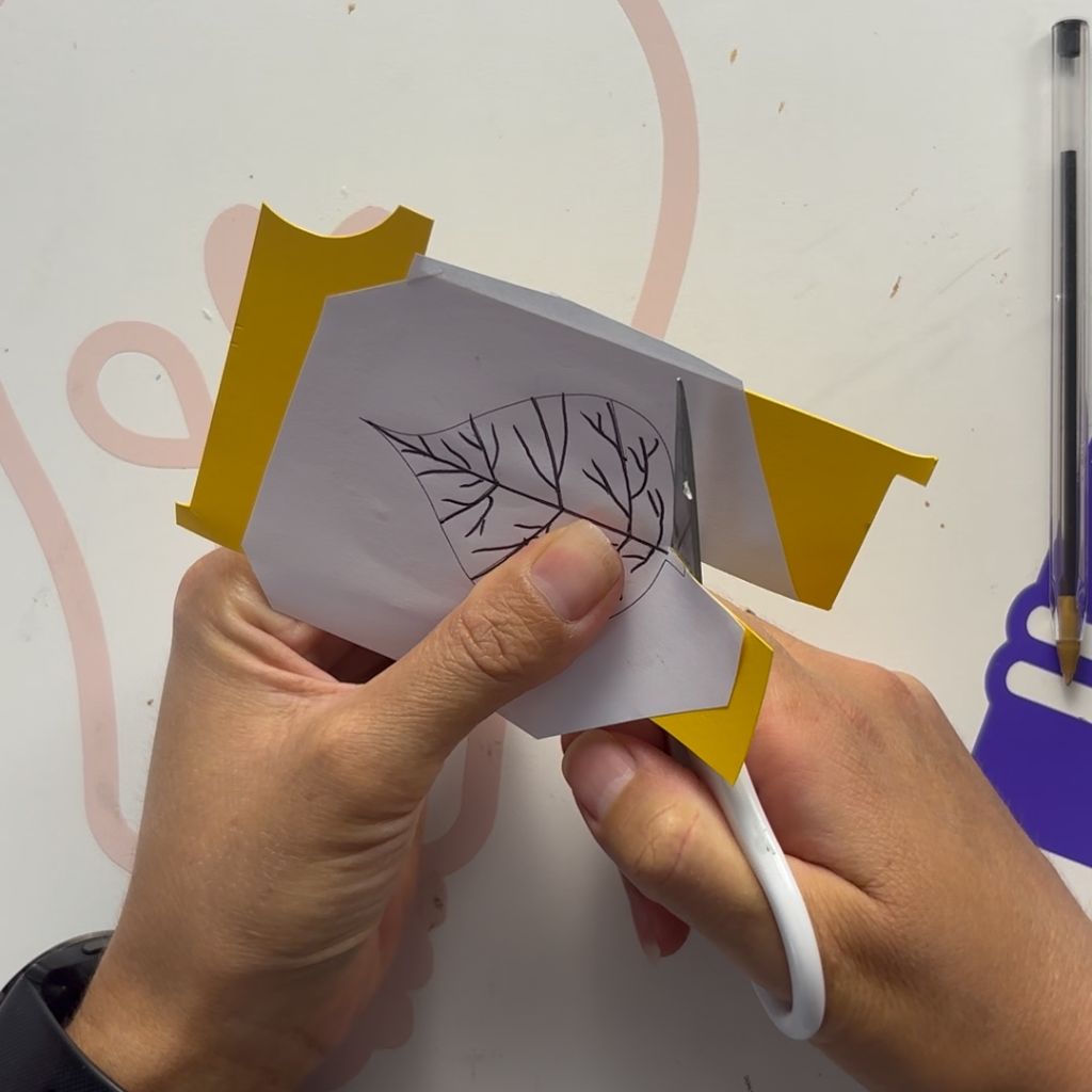 Etape 6 du tuto pour créer un DIY autour de l'automne avec des feuilles en papier glissées entre les livres d'une bibliothèque