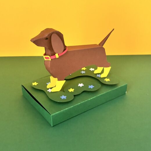 Kit créatif original permettant de créer un teckel et ses accessoires. Ici il a revêtu son collier et est chaussé de bottes jaunes