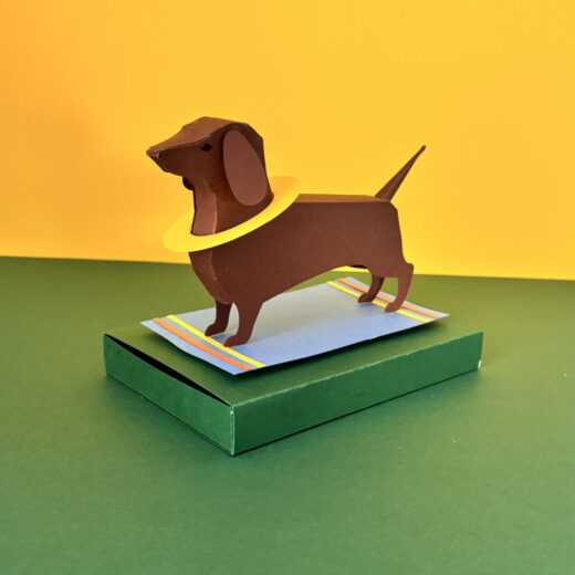 Kit créatif original permettant de créer un teckel et ses accessoires. Ici il a revêtu une bouée jaune et est posé sur sa serviette